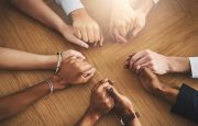 Closeup shot of a group of people sitting together at a table and holding hands